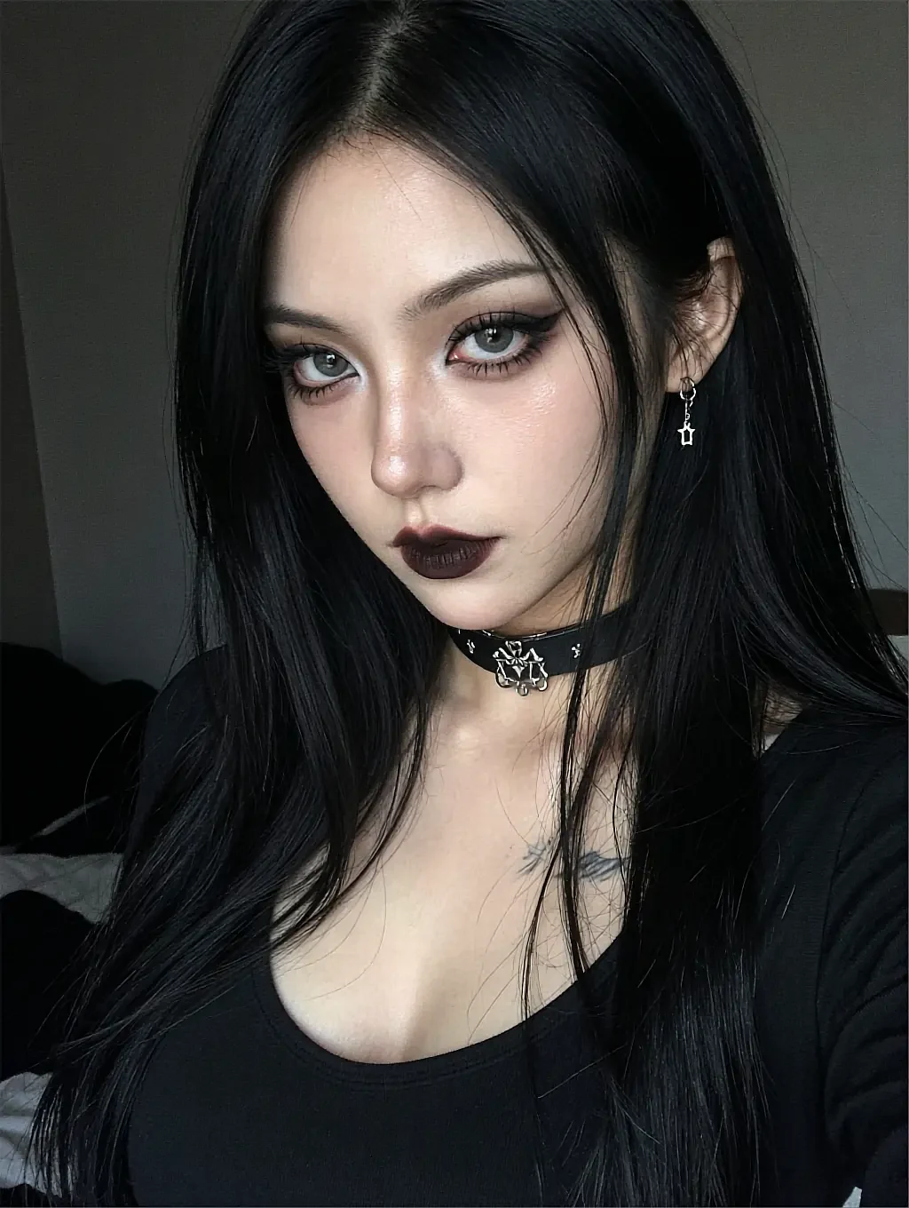 Fictional AI character with dark lipstick and a choker in a black long-sleeved top, dim room